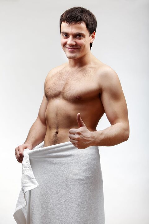 man in a towel is satisfied with the increased size of his penis